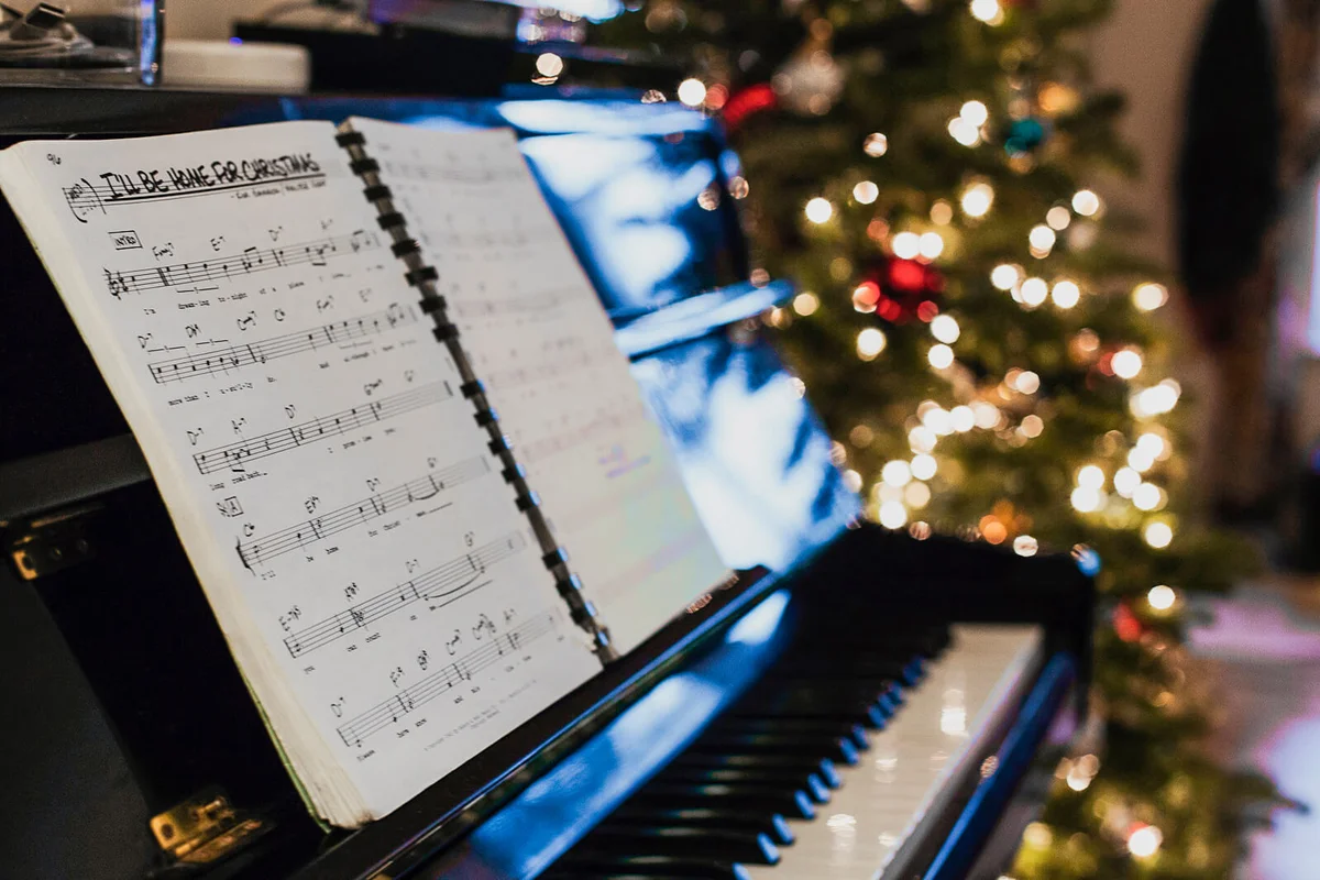 Sheet music on piano, Christmas tree in background