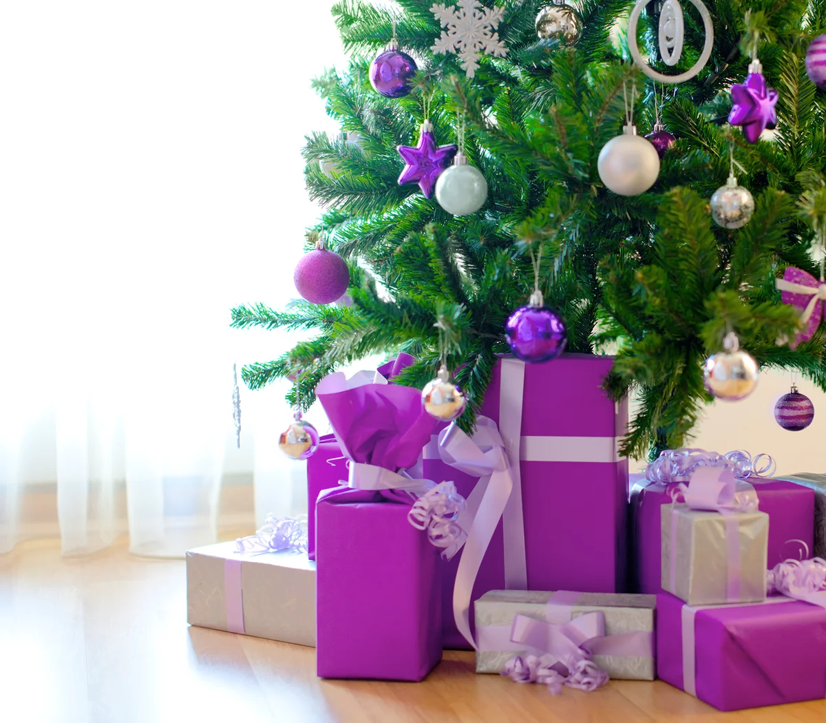 Christmas tree with beautiful violet and white ornaments and lot of presents.