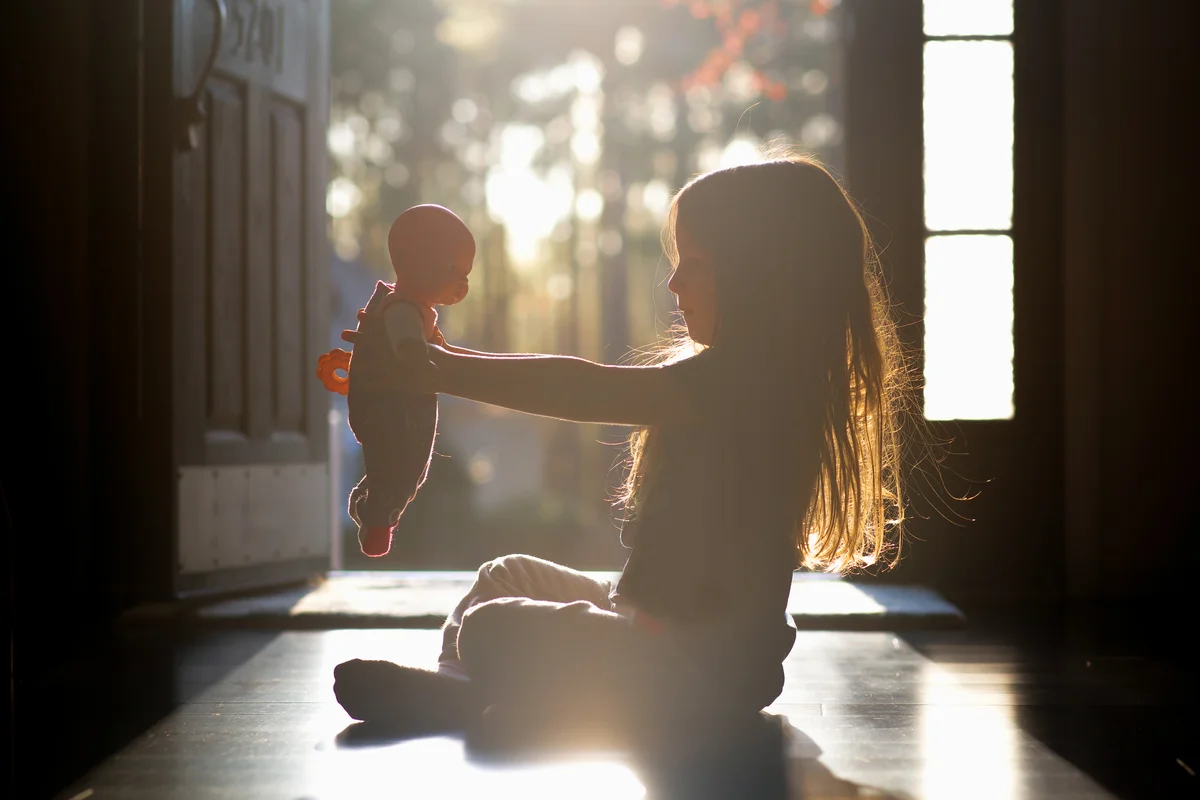 Young girl sitting in a hallway holding her baby doll