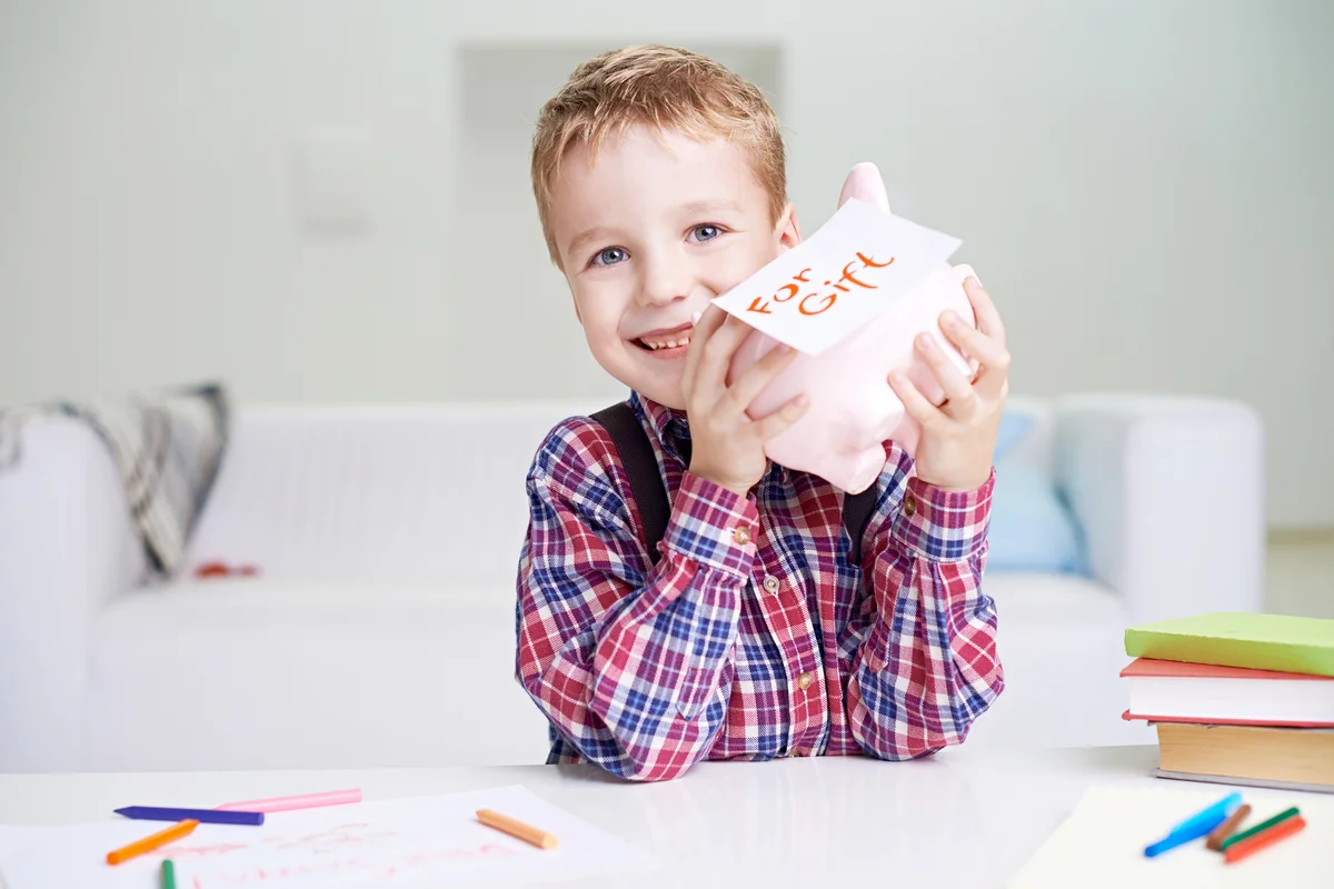Boy holding his Piggy Bank and smiling cheerfully
