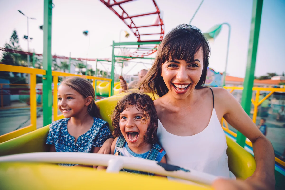Little son and daughter with mother on roller coaster ride