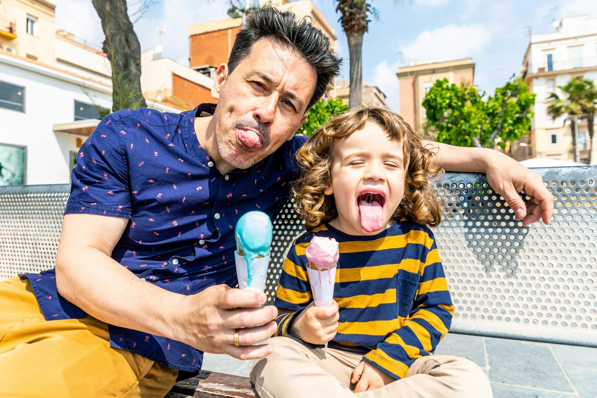 Happy father and son sitting on bench enjoying an ice cream