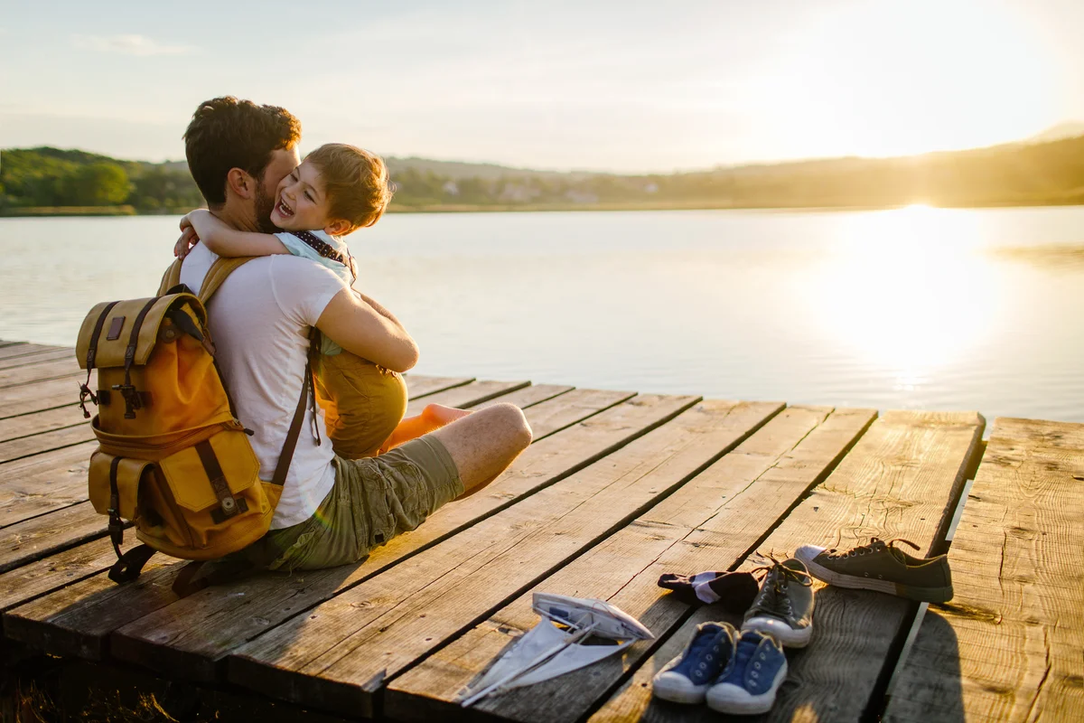 Young man and his son spending some quality time together while sitting on a lake dock