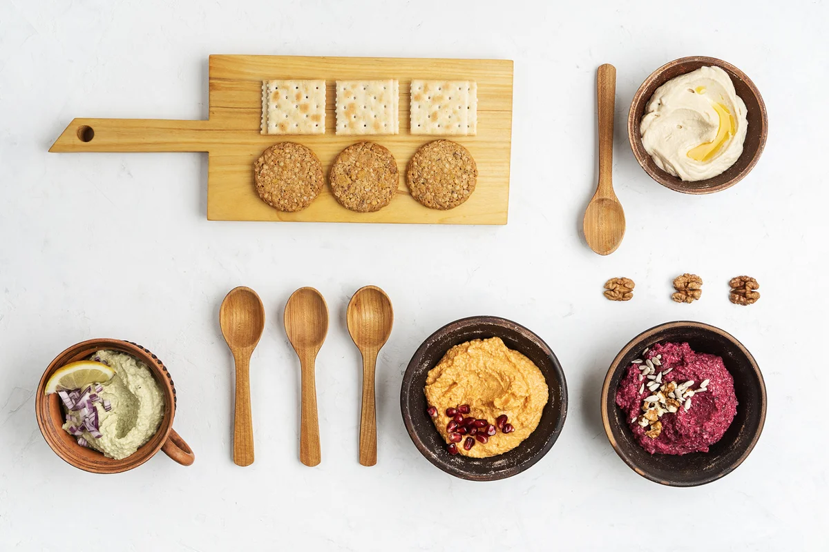 Crackers with assorted healthy snacks, gourmet dips in knolling style