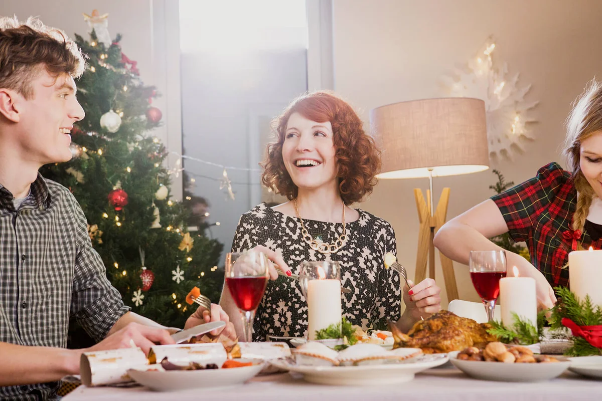 Friends laughing and eating Christmas dinner