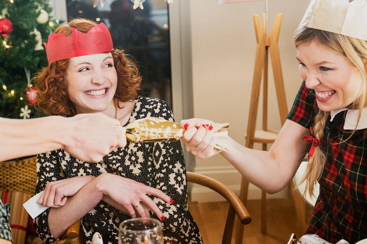 Friends pulling crackers at Christmas dinner party