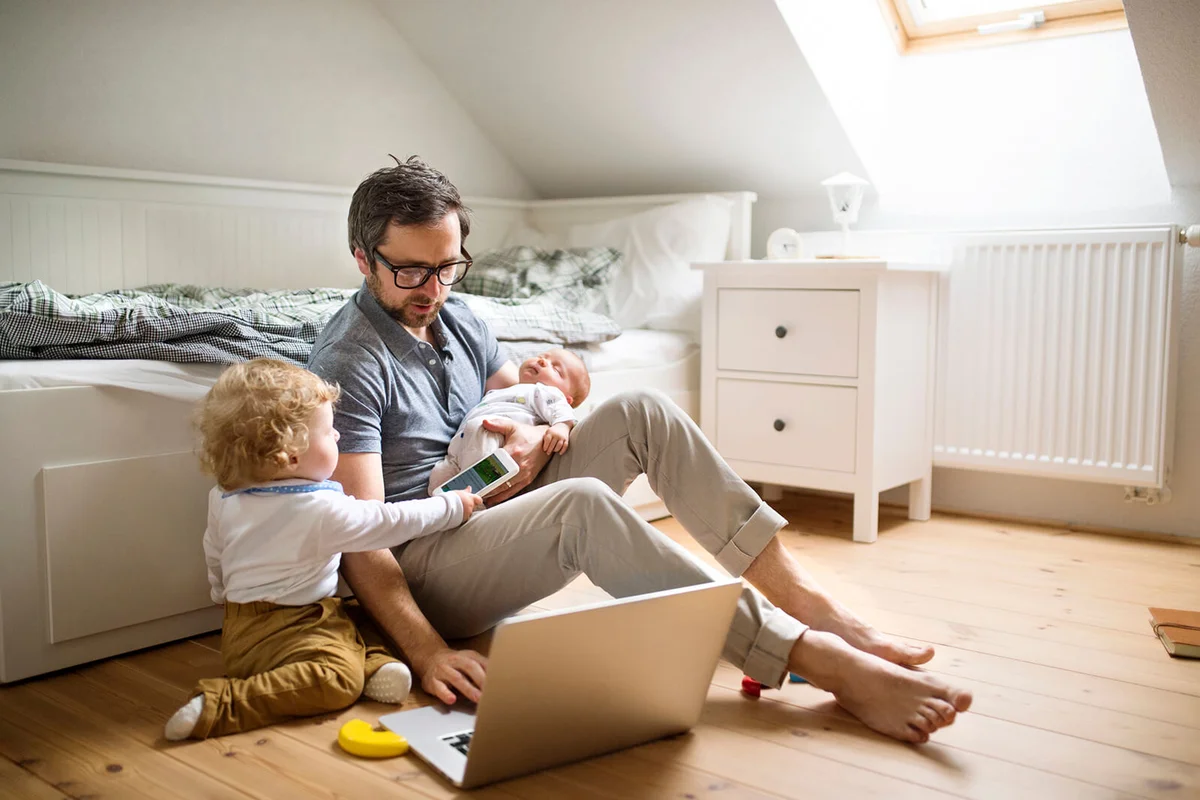 Father with his little son and baby daughter working from home