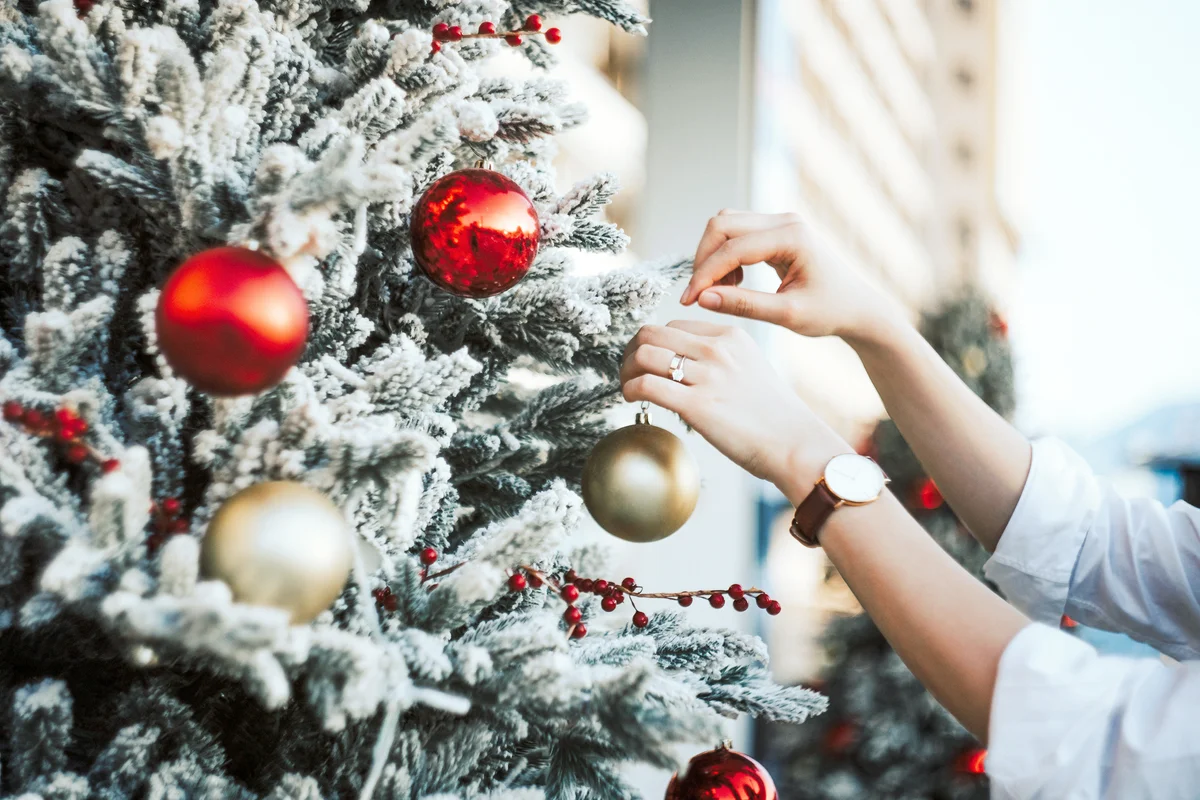 Woman decorating and hanging baubles on Christmas tree
