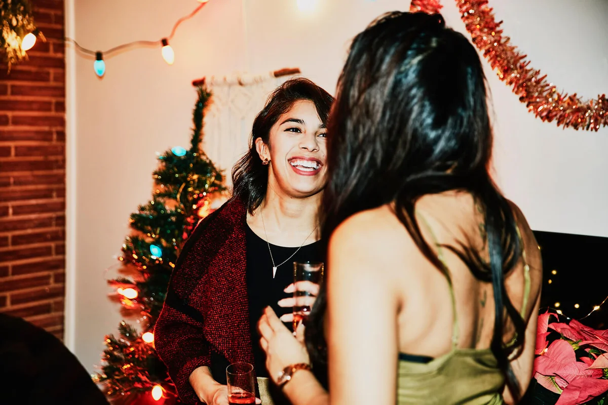 Laughing female friends in discussion during holiday party in home