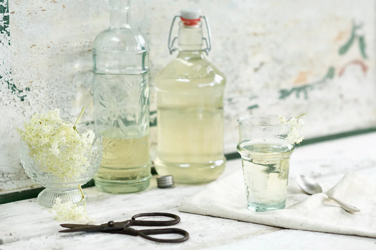 Glass bottles of elderflower sirup and elderflowers