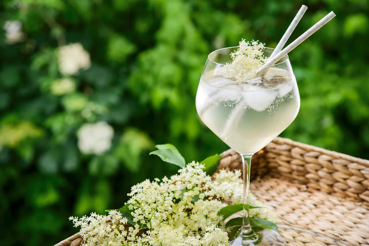 elderflower cocktail on a cork tray in a garden