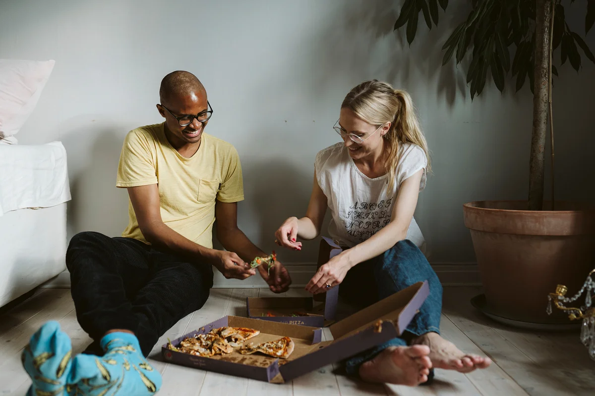 Couple sitting on floor and having pizza