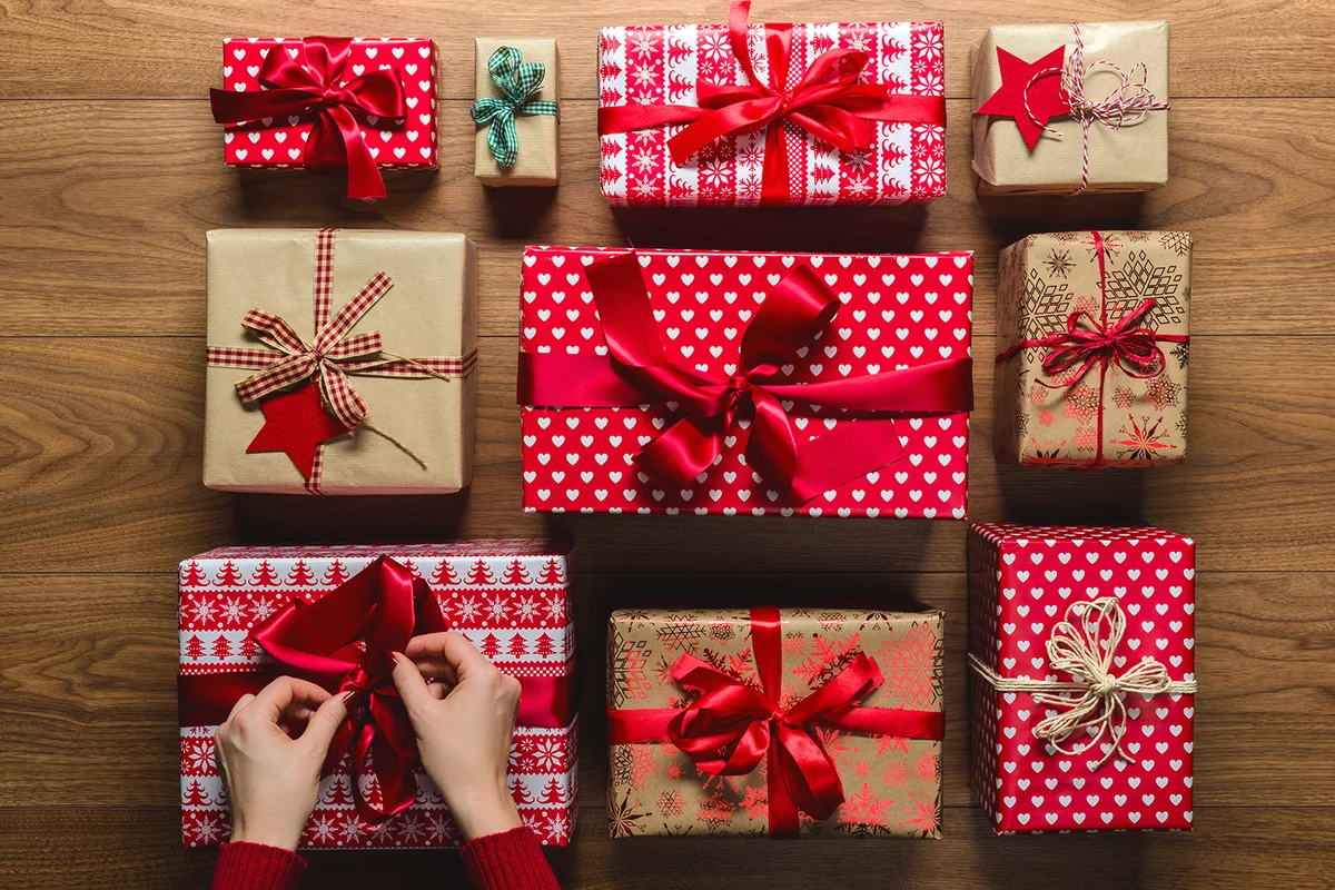 Woman Arranging Christmas Presents On Hardwood Floor