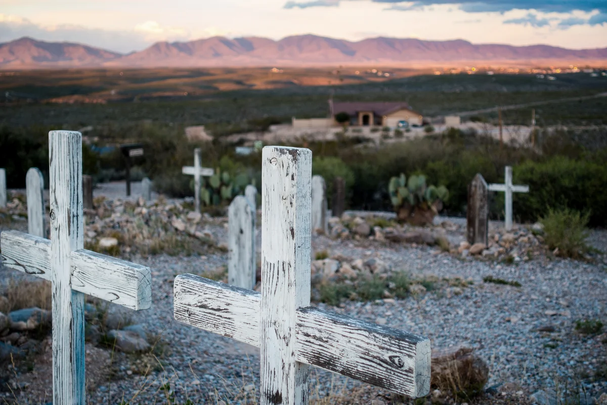 Two wooden cross grave markers overlooking sunset over hills