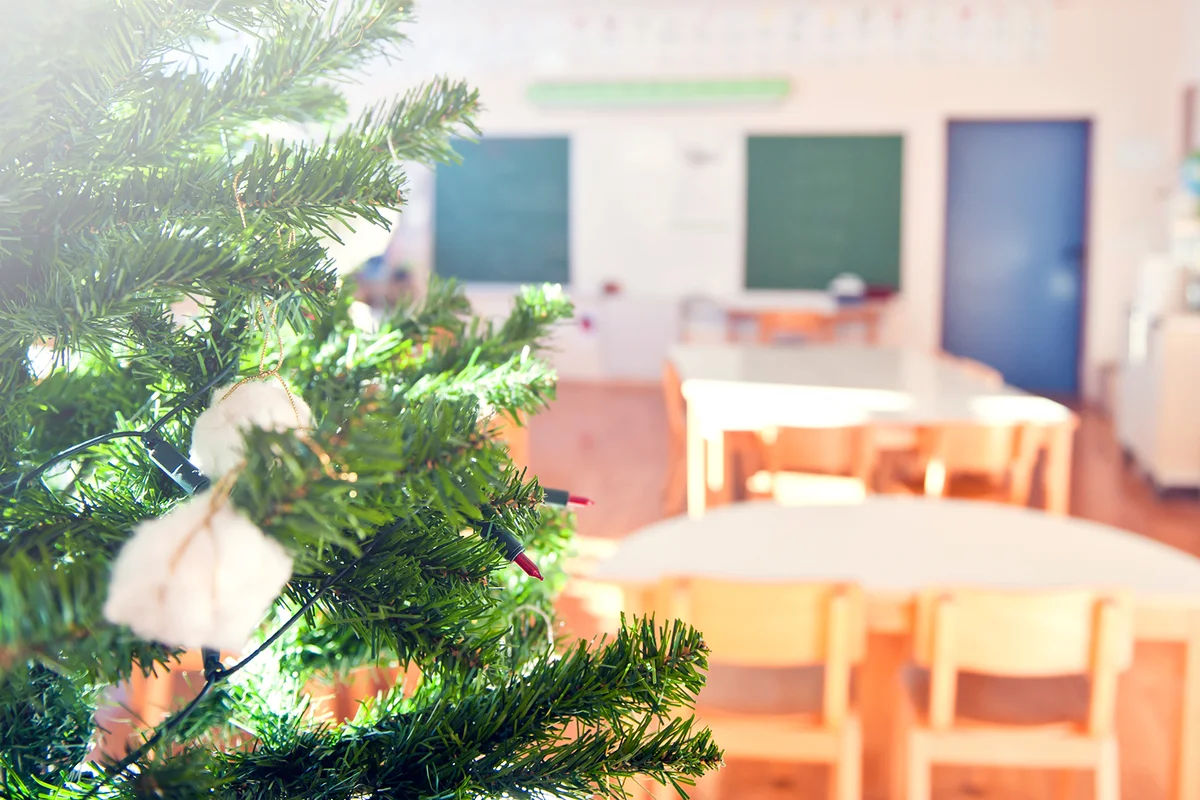 Christmas tree in school classroom, traditional wooden desks and chairs and blackboard