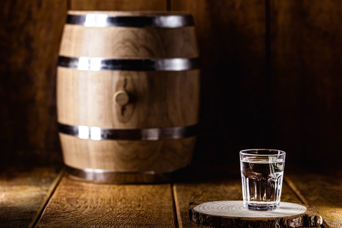 Old rustic oak barrel and glasses of high quality distilled alcohol