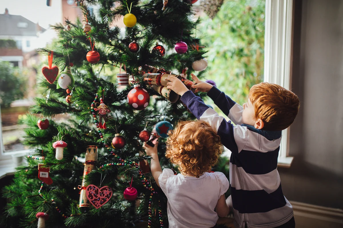 Siblings decorating the Christmas tree in their home