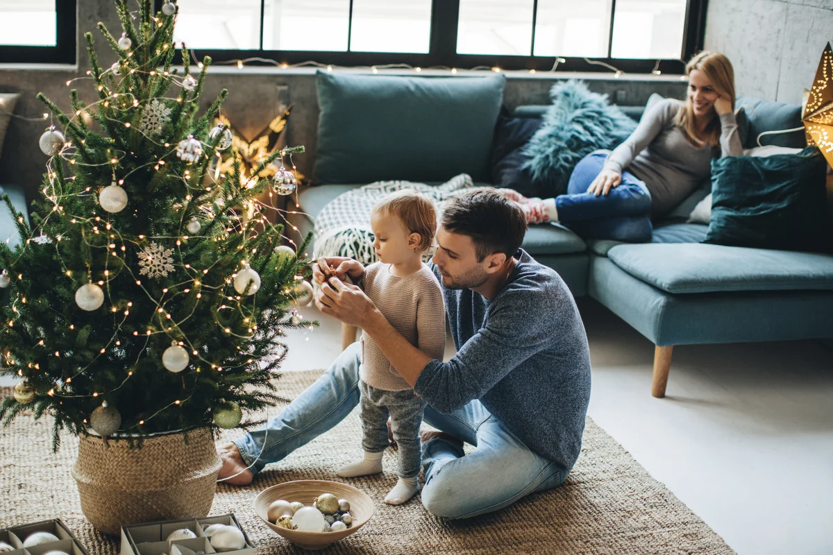 Family with one child decorating Christmas tree.