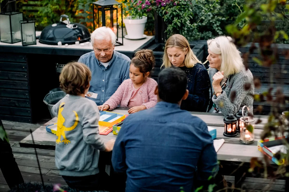 High angle view of family playing board game on table while sitting in patio