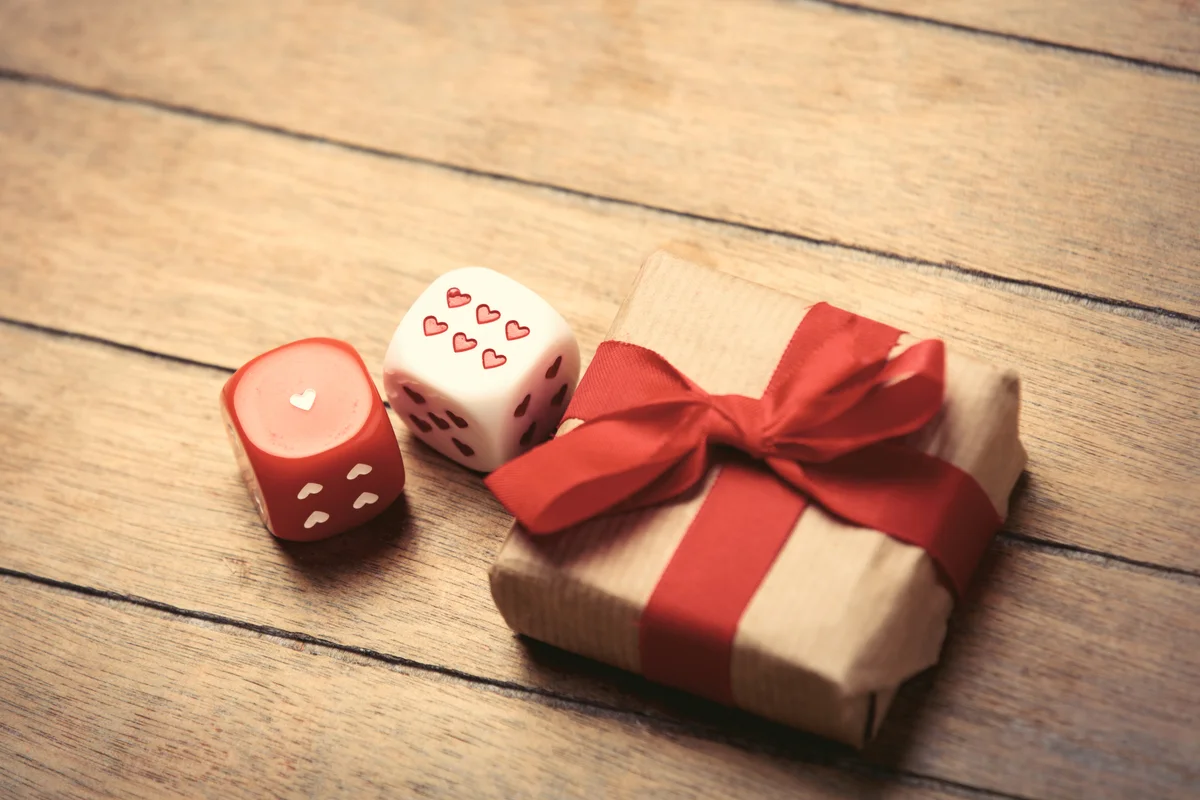 Beautiful gift and small dice on the wonderful brown wooden background