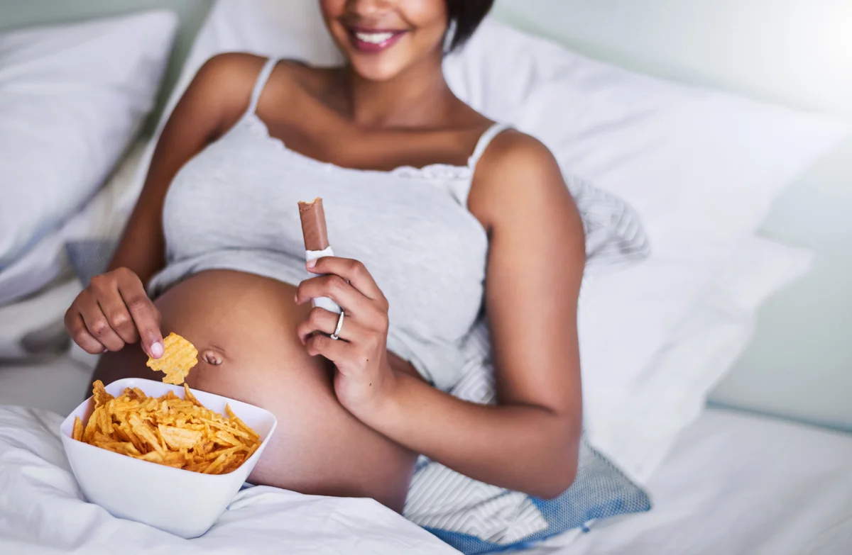 pregnant woman enjoying potato chips in bed