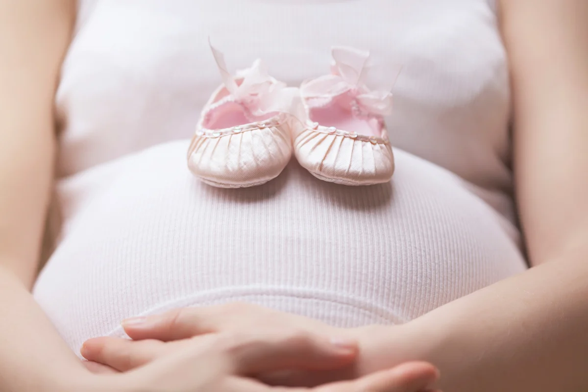 Pregnant woman and pink baby shoes