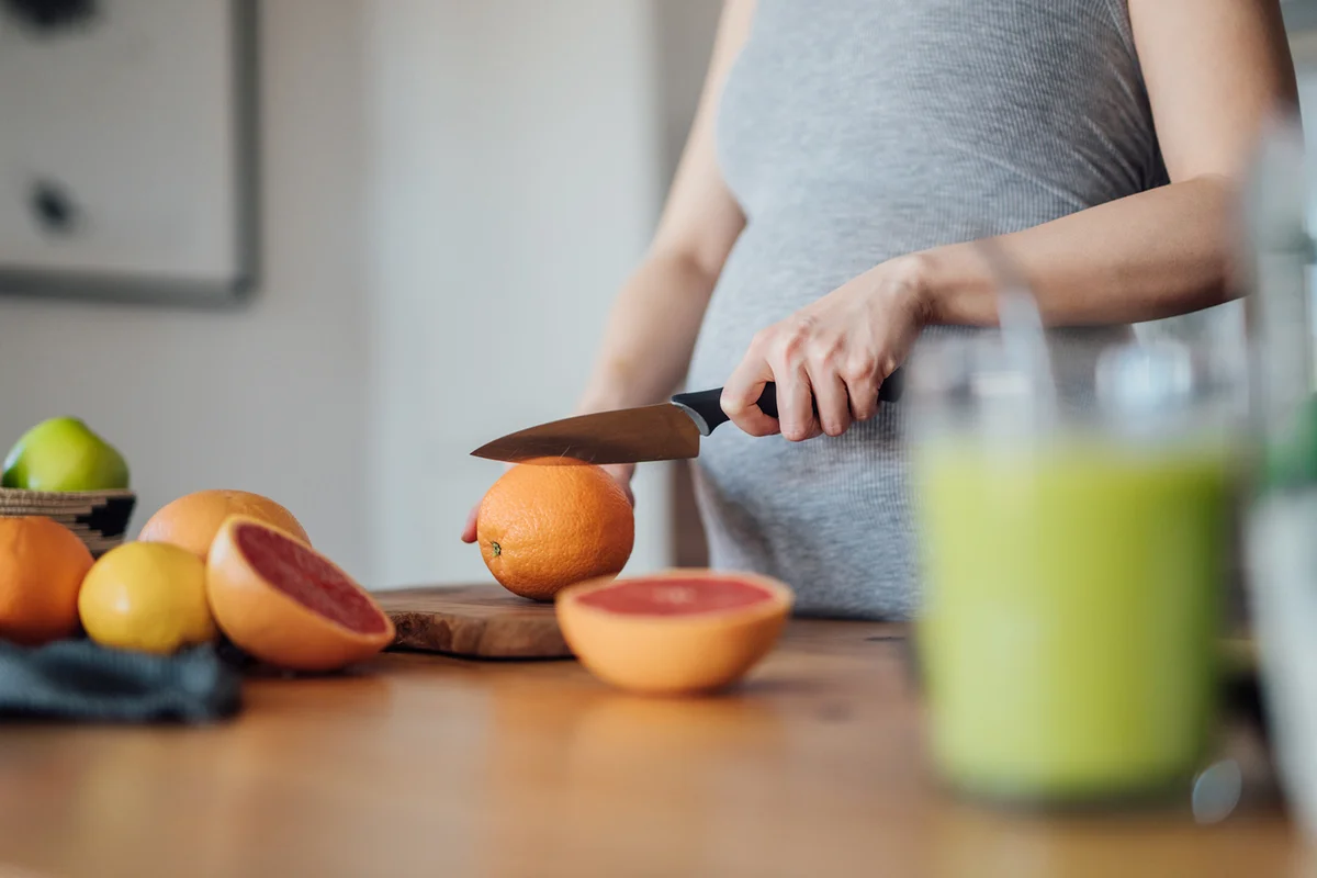 Pregnant woman making fresh homemade citrus fruit juice