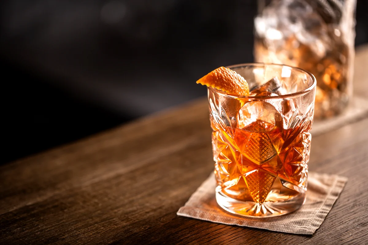 Pumpkin old fashioned whiskey drink on ice with orange zest garnish
