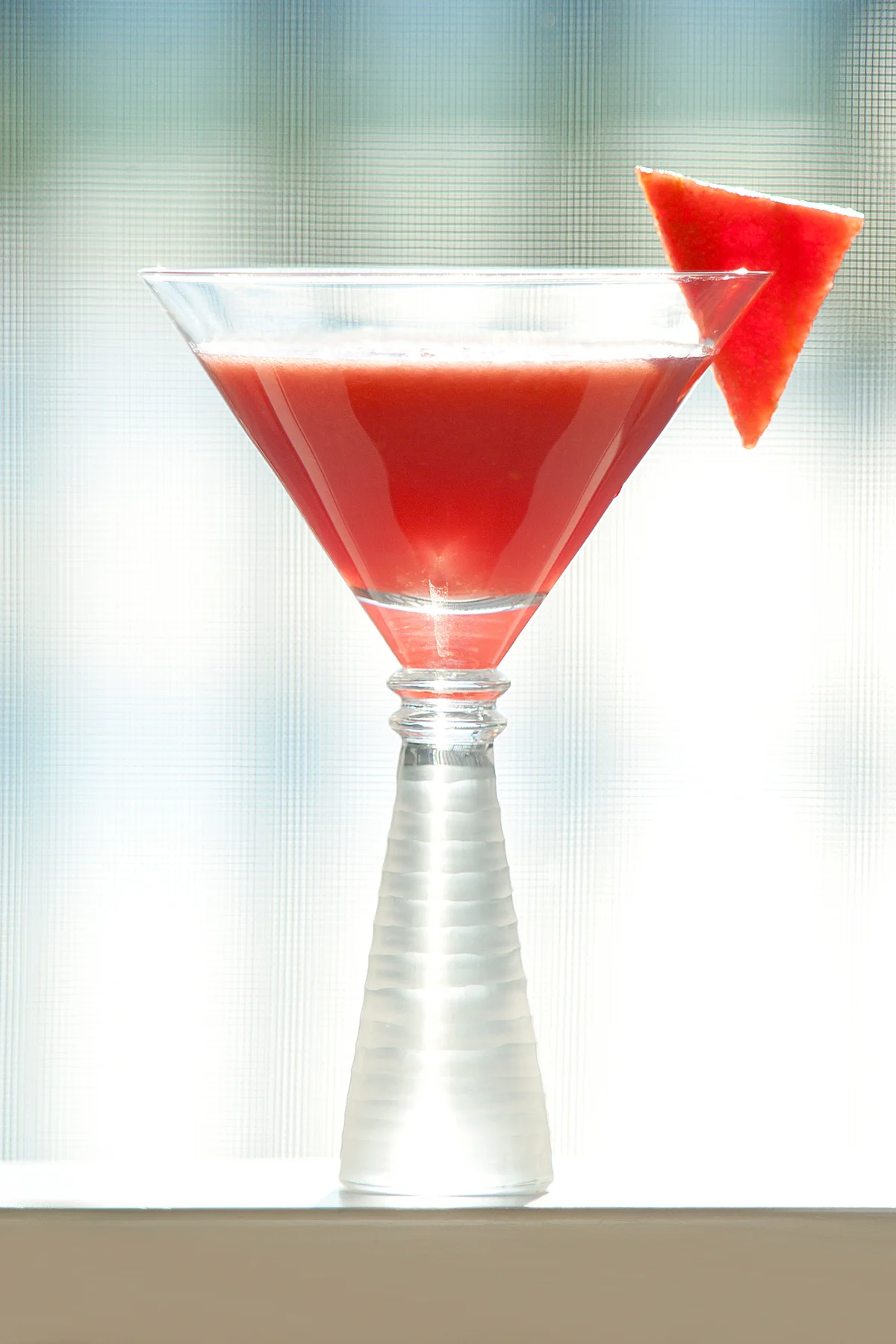 Watermelon cocktail with a wedge of sliced watermelon as a garnish