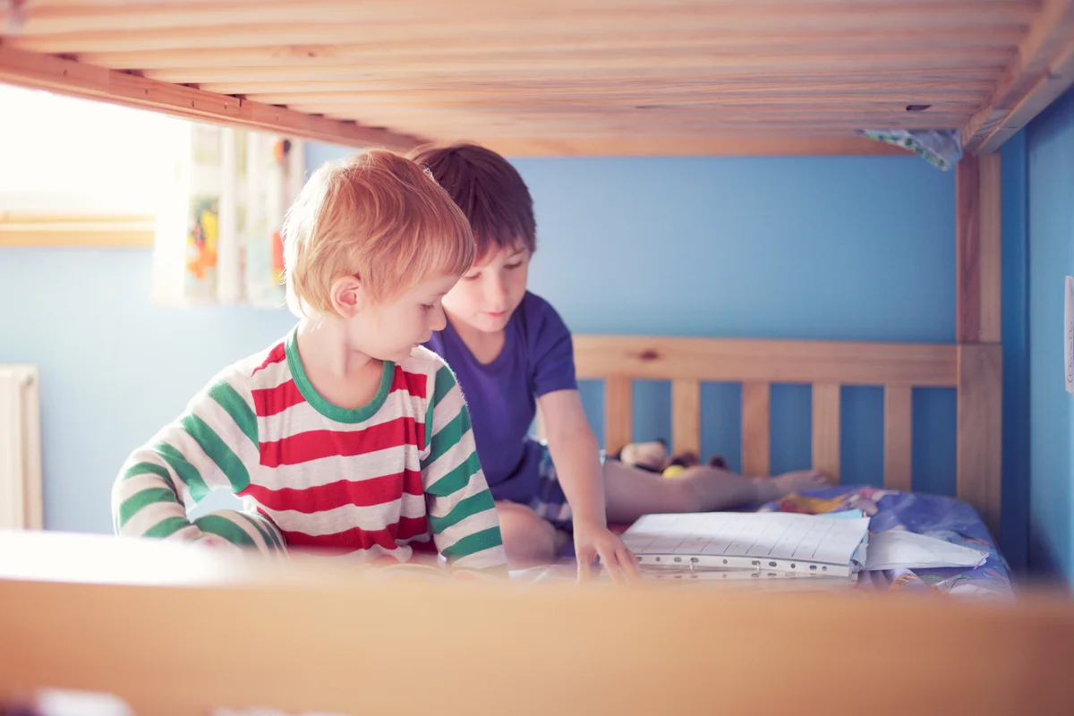 Brothers in  pyjamas sitting on the lower bed of a bunk bed