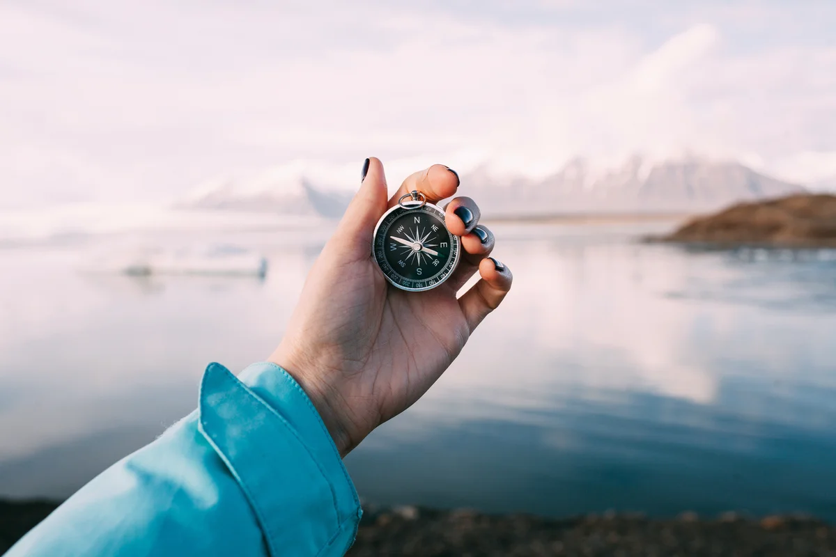 Young woman holding a compass in front of the Glacier Lagoon in Iceland