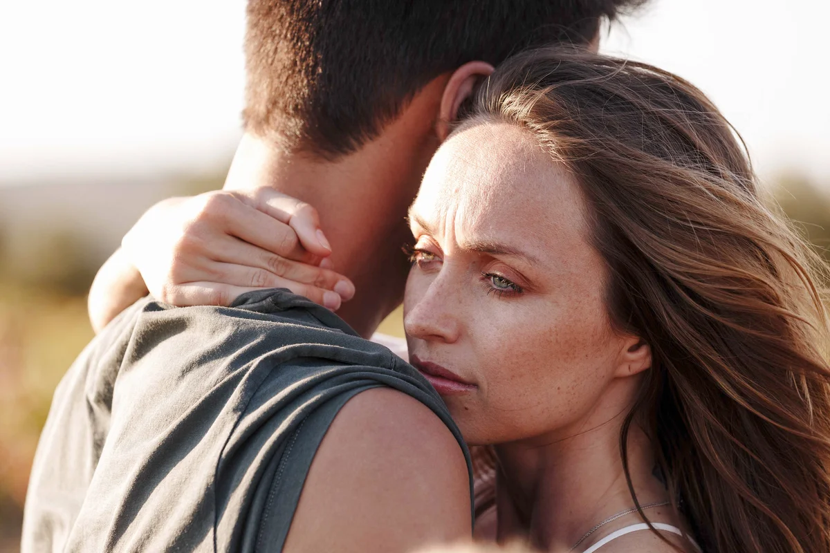 Couple hugging, woman looking worried