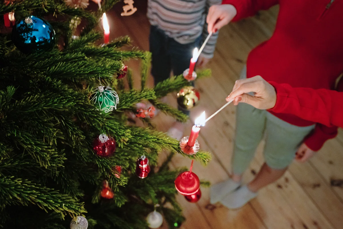 family lighting the candles of the christmas tree with matches