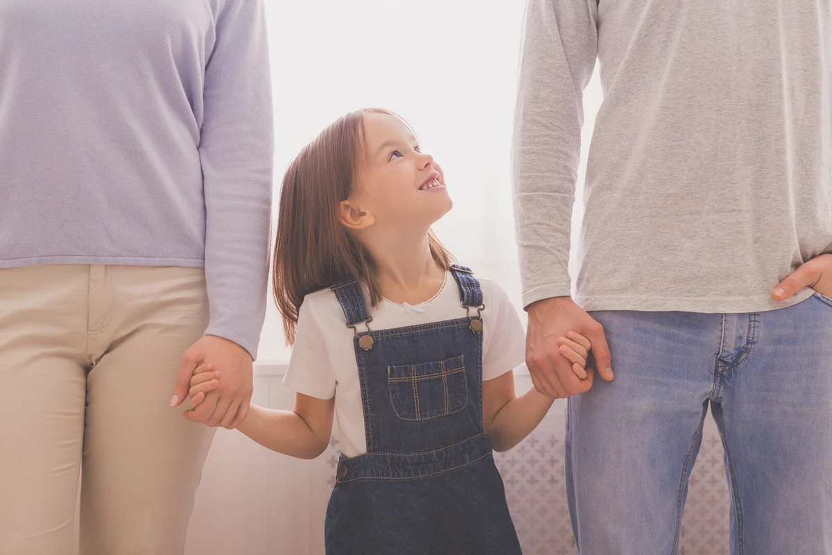 Happy Little Girl Holding Hands With Parents