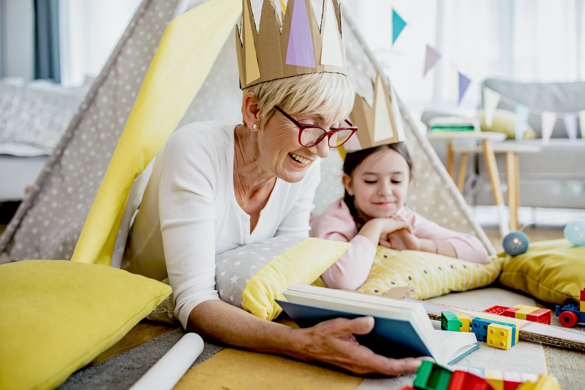 Grandmother reading book to her grandmother in a tent