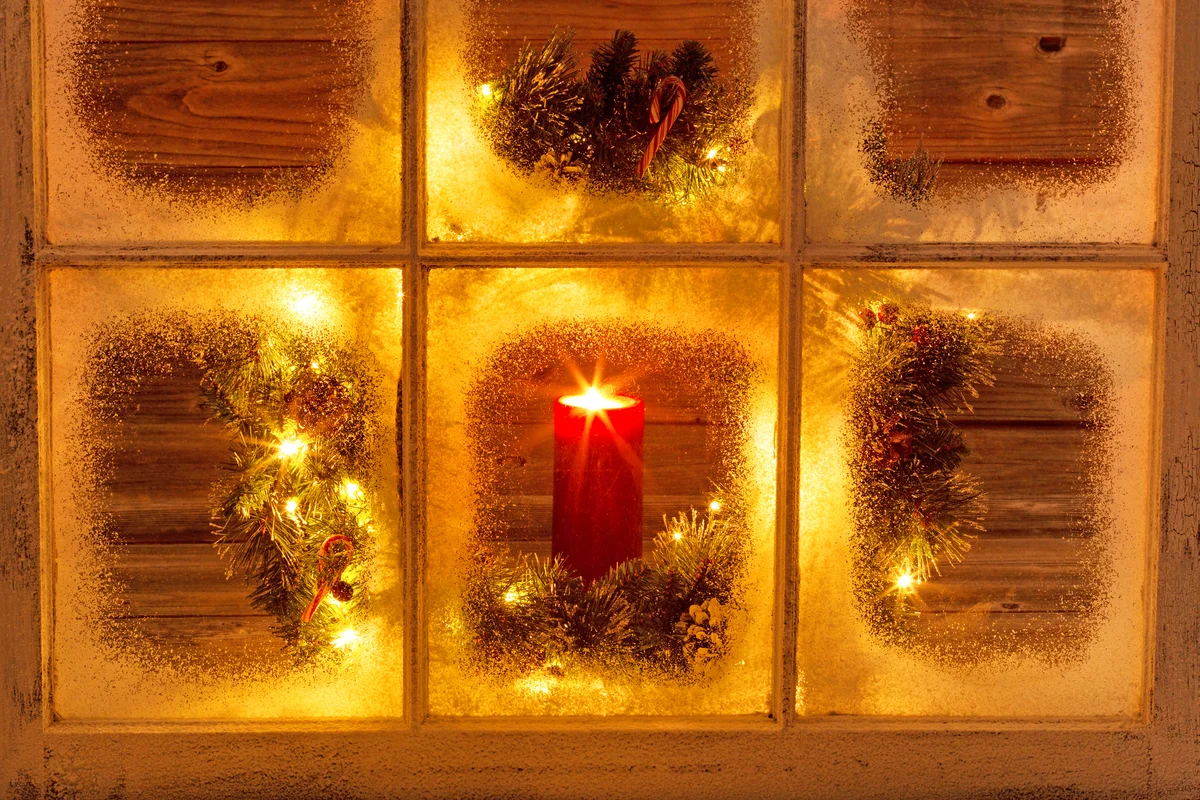 Burning Candle With Christmas Wreath Seen Through Frosted Glass Window