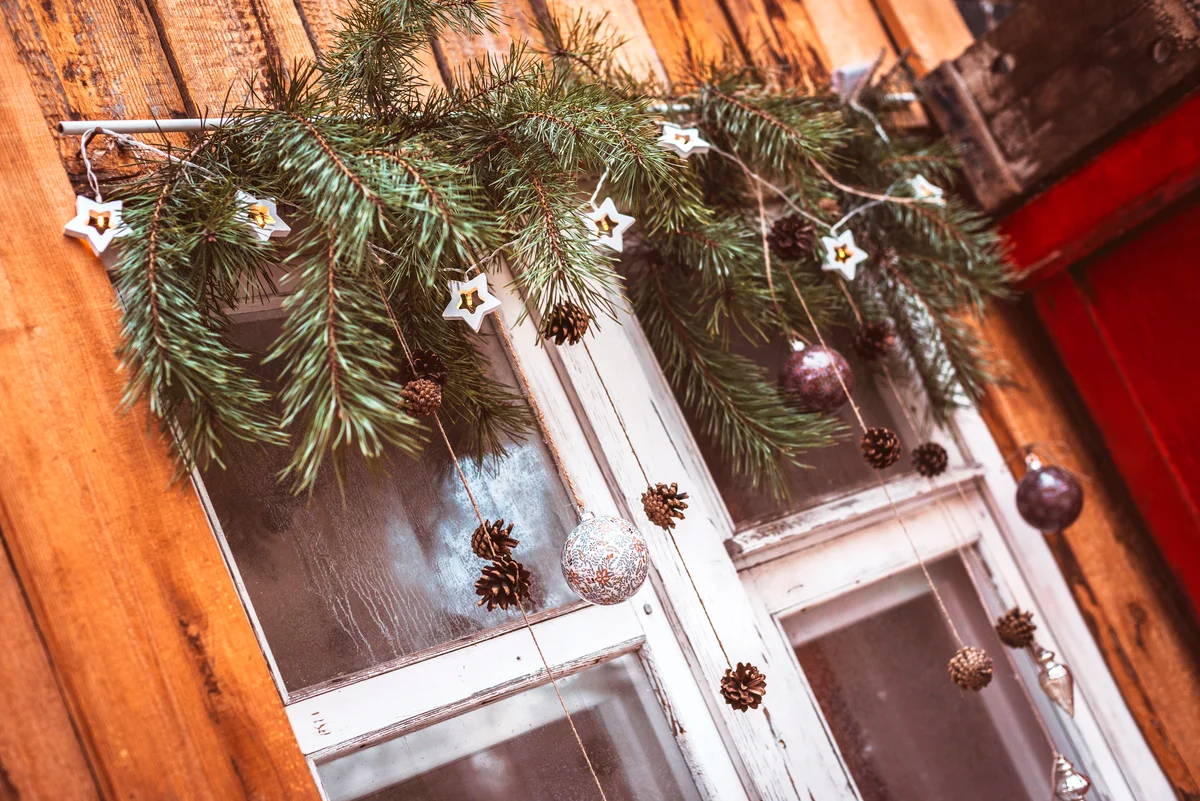 Festive Christmas window decoration with fir branches, garlands and cones