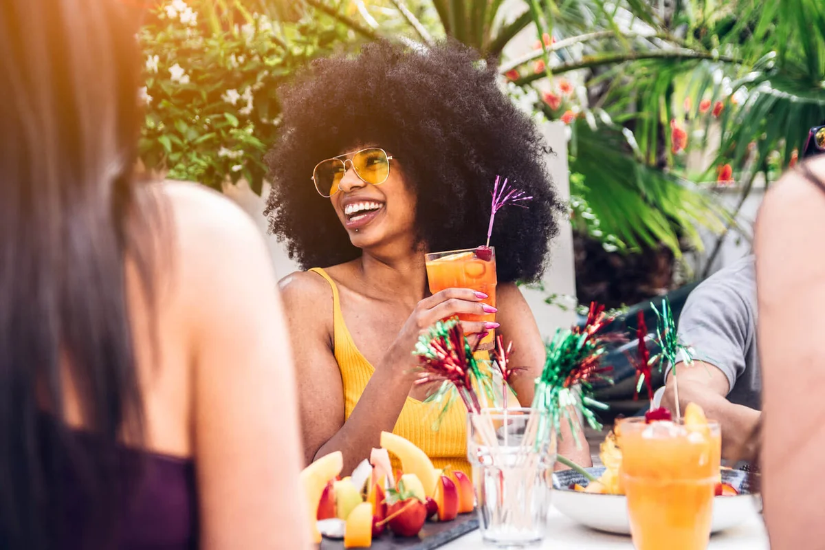 Happy Young Woman Holding Juice While Sitting Outdoors