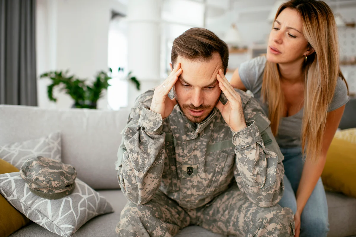 Depressed soldier sitting on sofa with his wife