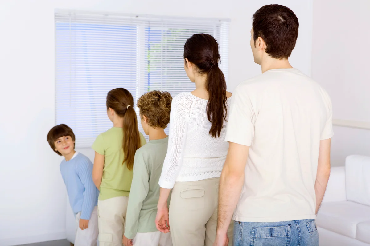 Family lined up shortest to tallest, youngest boy looking over shoulder at rest of family