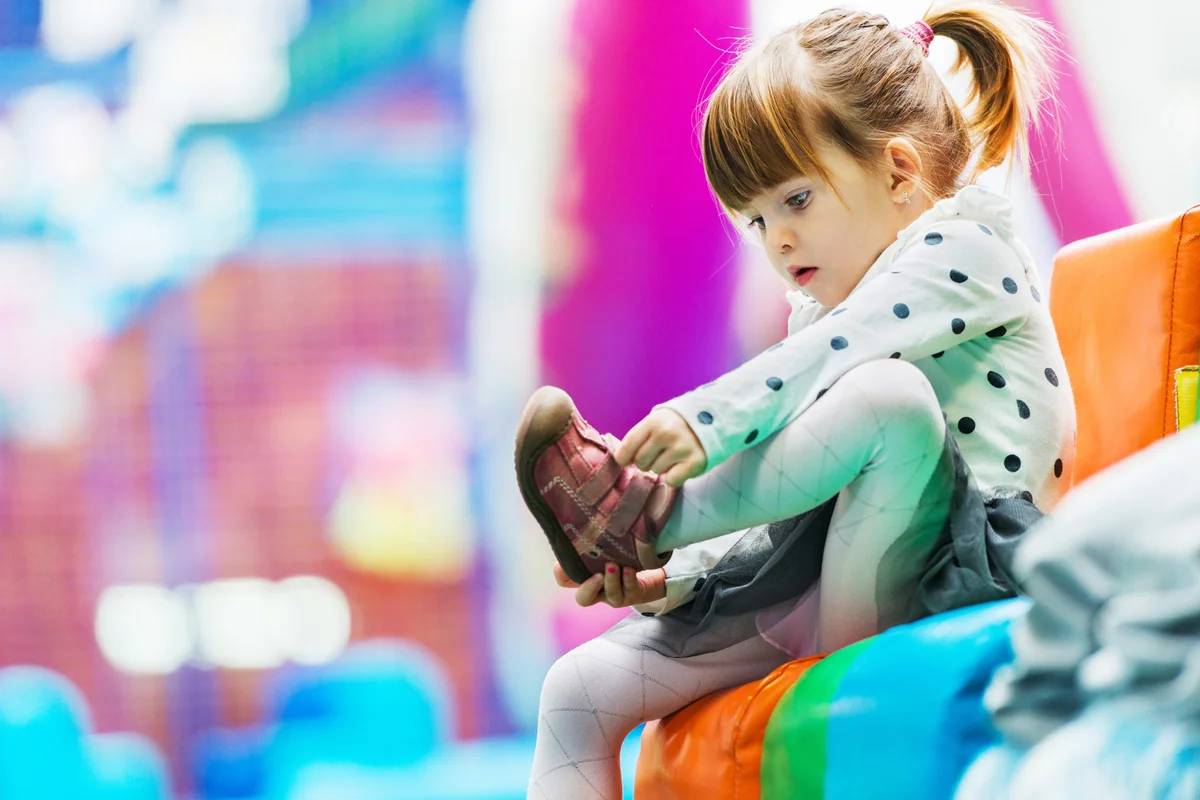 Little girl taking her shoes off in the playroom