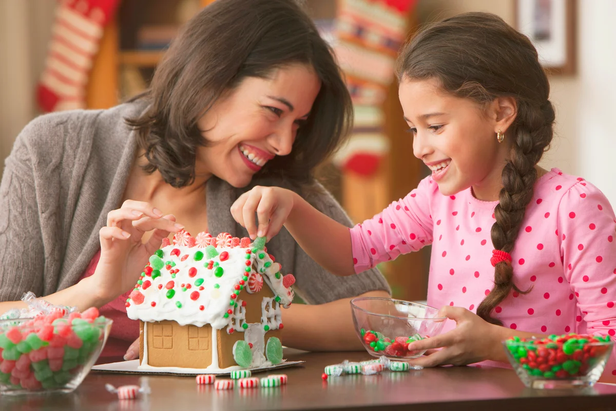 Mother and daughter decorating gingerbread house
