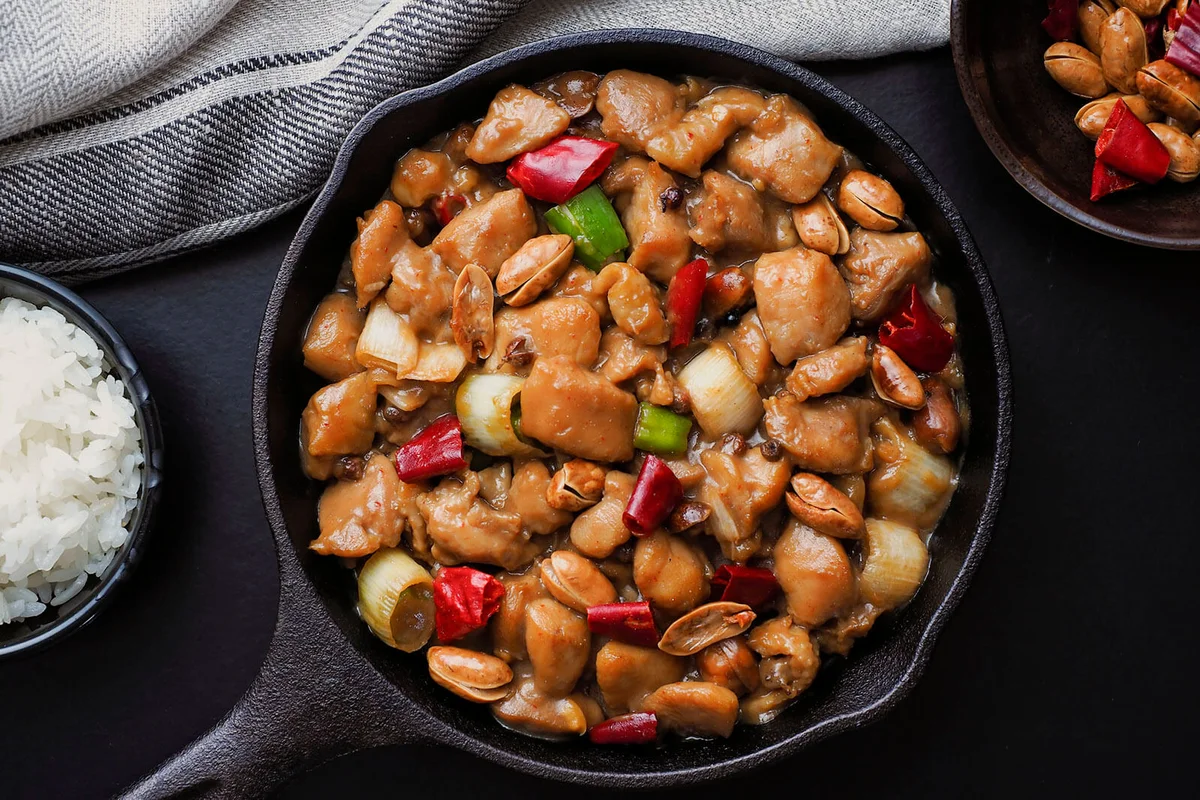 Delicious kung pao chicken with pepper, shallots and peanuts in a wok pan