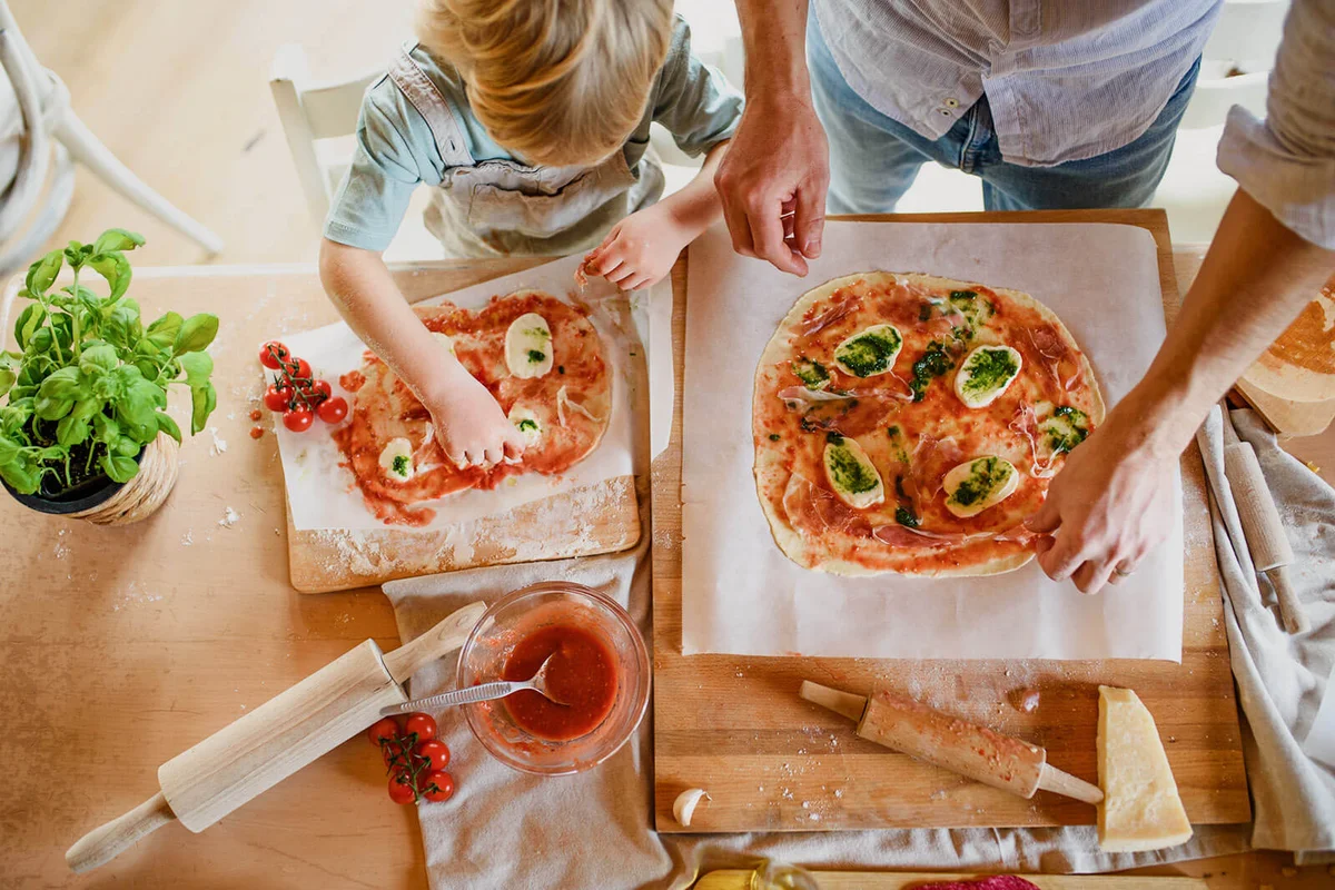 father with small son making pizza at home, cooking