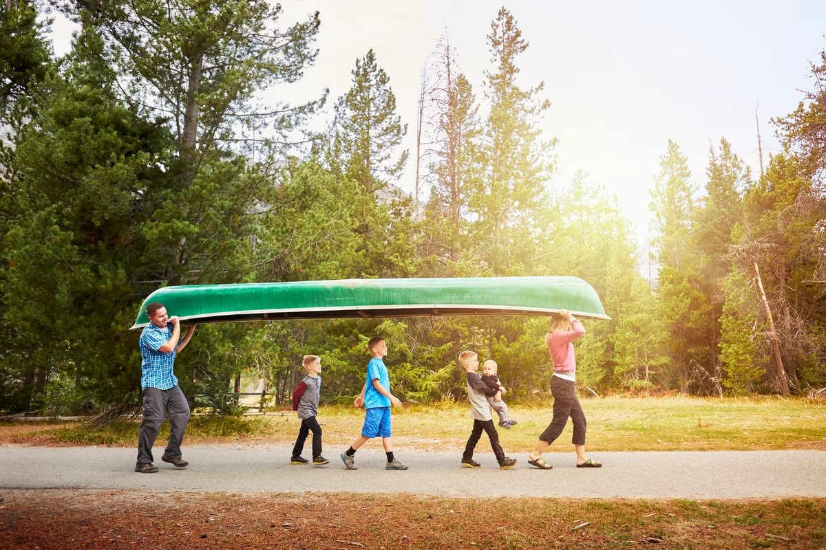 Family with four children carrying canoe