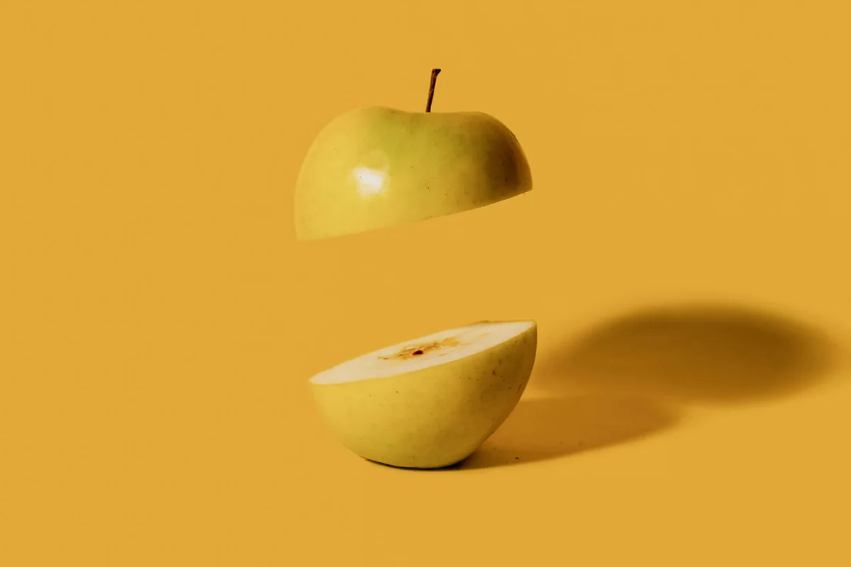 Green apple sliced in half with one half floating in air