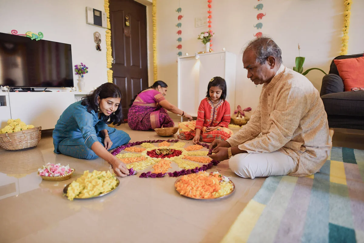 Multi-generation Indian family making floral rangoli for Diwali celebration