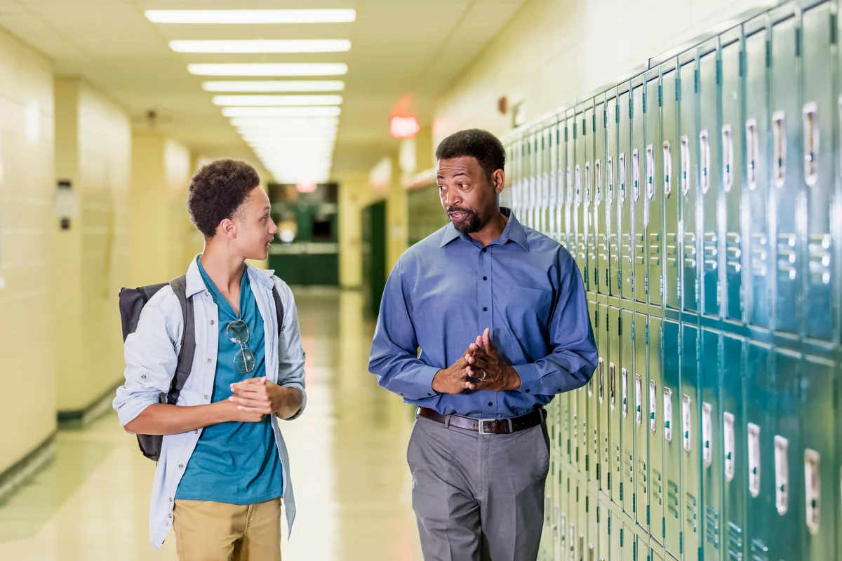 Teacher and high school student walking in hallway