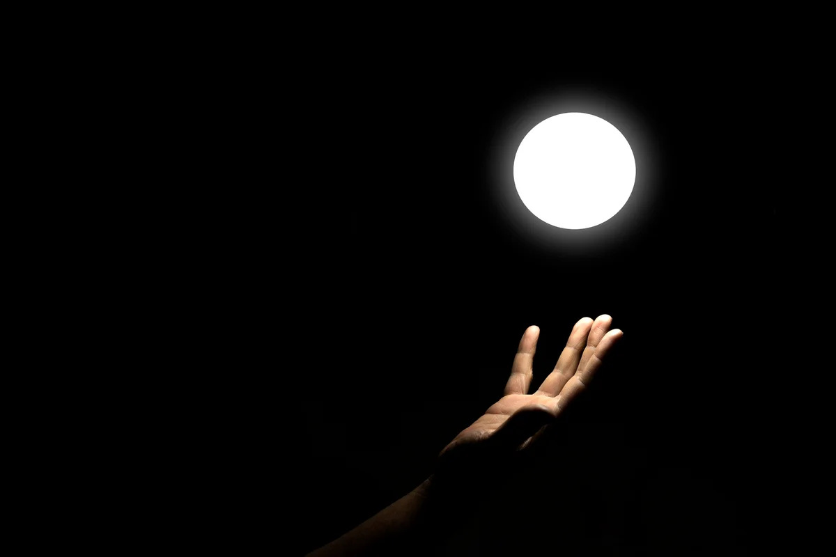 Hand Touching Glowing Source of White Light