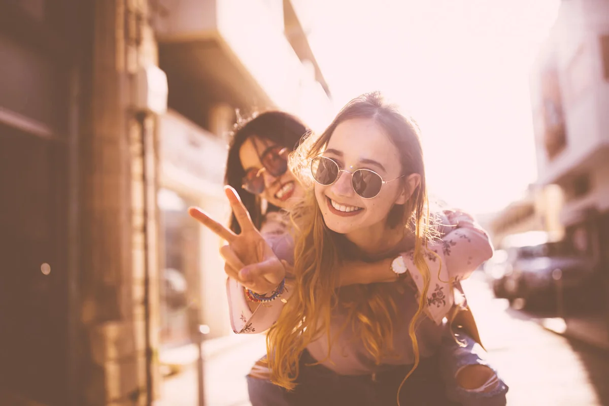 Young woman on piggyback ride doing the peace sign